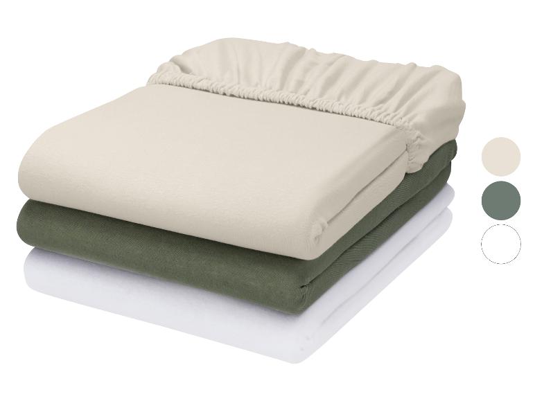 Stapel von drei Spannbettlaken in Beige, Grün und Weiß mit Farbmustern.