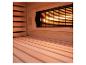 Sauna-Innenansicht mit Holzbänken und beleuchtetem Heizstrahler hinter einem Gitter.
