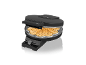 Schwarzes Waffeleisen offen mit einer herzförmigen Waffel darin, auf schwarzem Hintergrund.