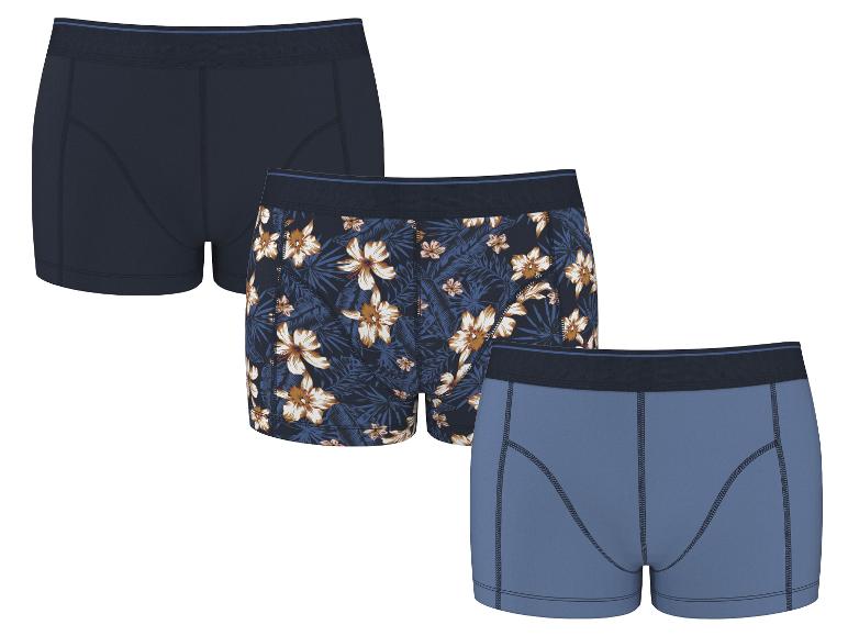 Drei Herren-Baumwollboxershorts: eine marineblau, eine mit Blumenmuster und eine hellblau.