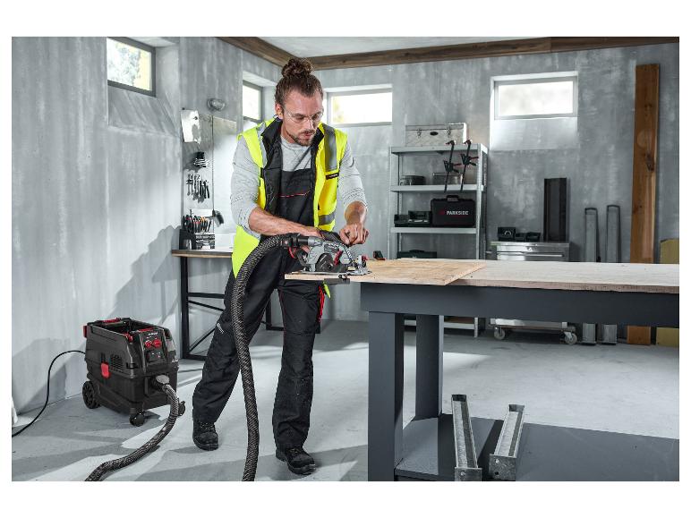 Ein Mann in einer PARKSIDE PERFORMANCE® Arbeitslatzhose bedient eine Handkreissäge mit Sauger.