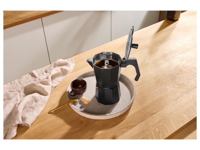 Schwarze Mokkakanne mit Kaffee, einer Tasse und Keksen auf einem Tablett auf einer Holzarbeitsplatte.