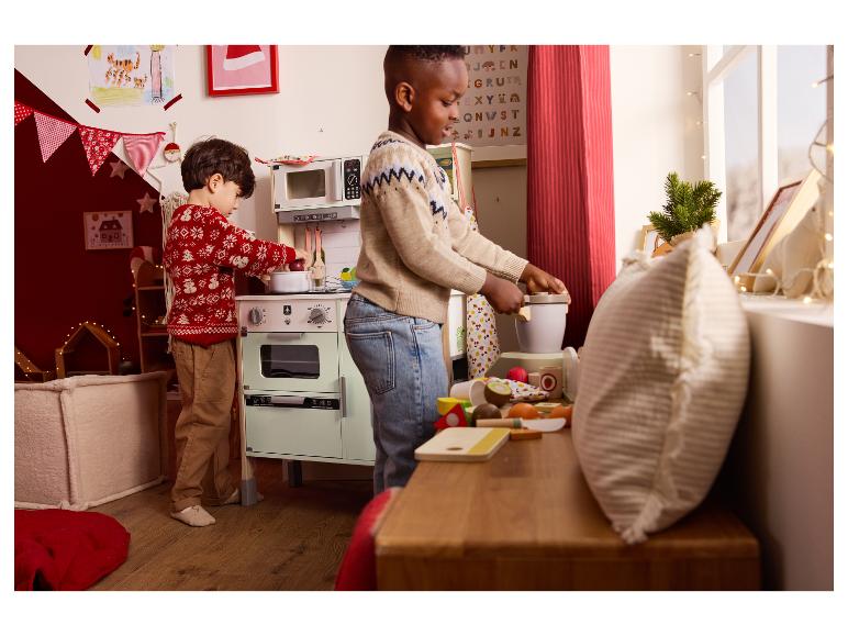 Zwei Kinder spielen mit einer Spielküche und Holzlebensmitteln.