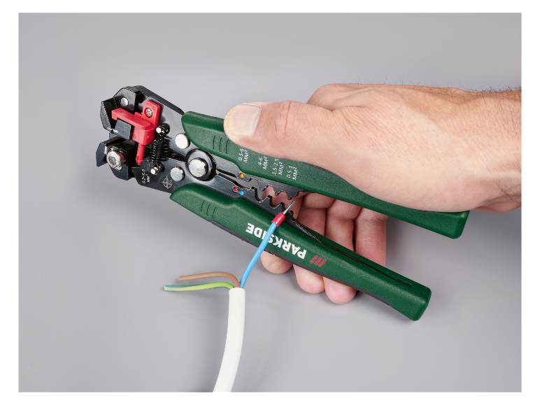 Hand hält automatische Abisolierzange, isoliert ein blaues Kabel ab, mit anderen Kabeln sichtbar.