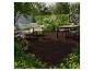 Holzterrasse mit Gartenmöbeln und Esstisch, umgeben von Grün und Blumen.