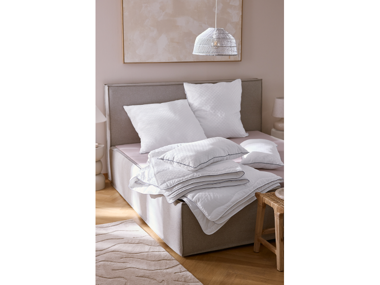 Bett mit weißen Kissen und Decken in einem Schlafzimmer.