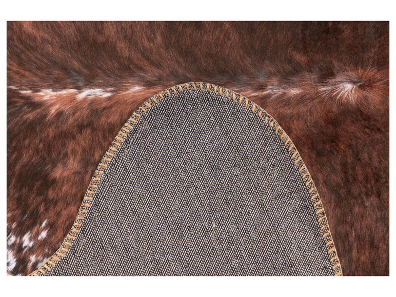 Ein brauner und weißer Fellteppich mit beigefarbenem Rand und grauer Unterseite.