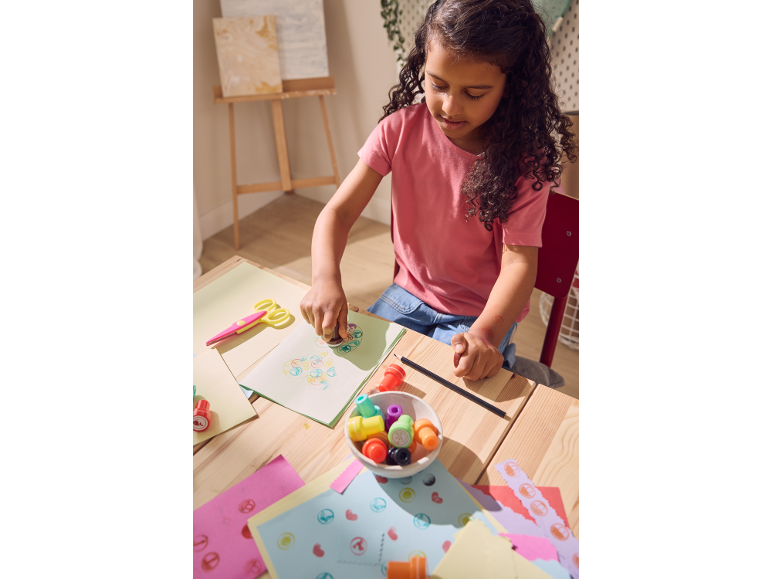 Mädchen stempelt mit bunten Stempeln auf Papier, kreatives Spielzeug.