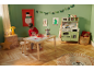 Kind spielt mit einer Holzküche und Spielzeugessen in einem weihnachtlich dekorierten Zimmer.