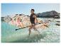 Frau in Schwimmweste mit SUP-Board und Paddel im Wasser.