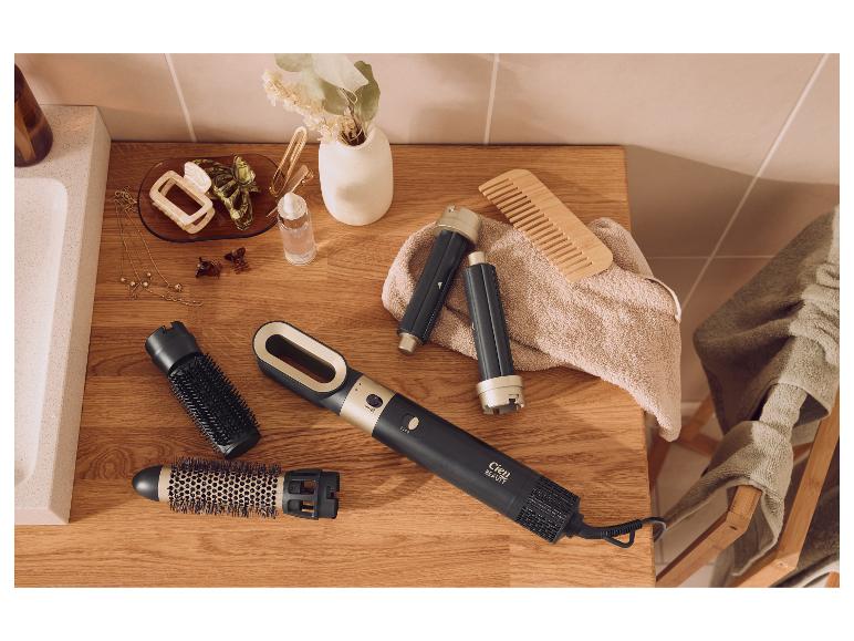 Cien Beauty Warmluftstyler mit austauschbaren Aufsätzen, Haarschmuck und einem Holzkamm auf einer Badezimmerablage.