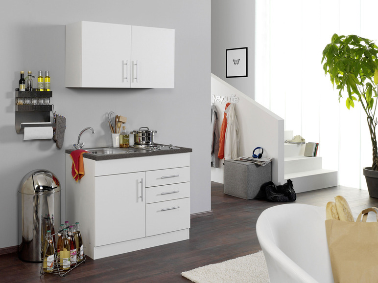 Ein weißer Küchenblock mit Spüle, Kochfeld und Schränken