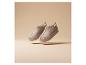 Zwei beige Wildleder-Slipper mit flauschigem Futter schweben vor beigem Hintergrund.