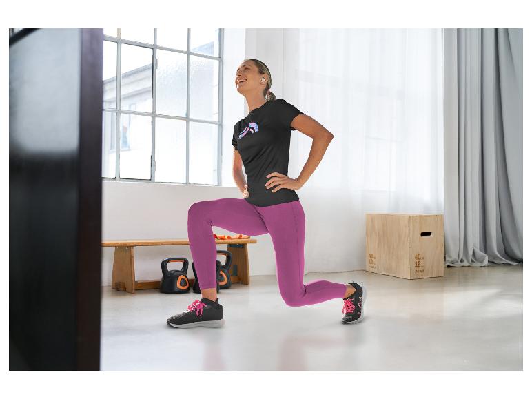 Frau in schwarzem Sport-T-Shirt und lila Leggings macht Ausfallschritte im Fitnessstudio.