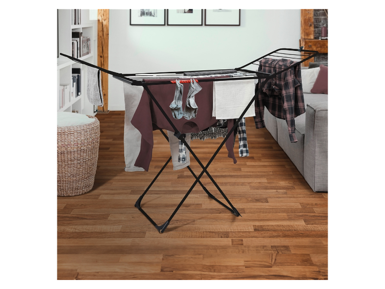 Schwarzer zusammenklappbarer Wäscheständer auf einem Holzboden.