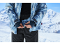 Nahaufnahme eines Mannes, der seine blau gemusterte Skijacke auf einem verschneiten Berg zuknöpft.