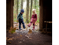 Zwei kleine Kinder in warmer Outdoor-Kleidung und Stiefeln spielen in einer Pfütze im Wald.