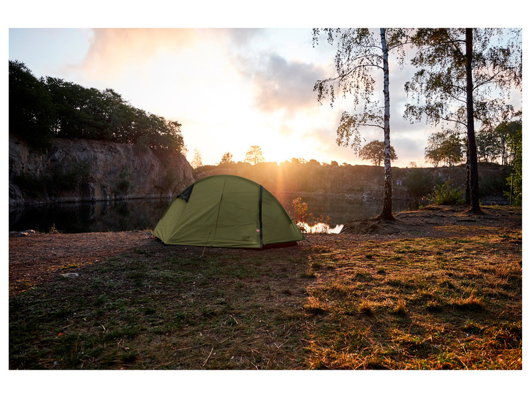 Ein grünes Zelt steht auf einer Wiese am See.