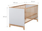 Ein weißes Babybett mit Holzlatten und Beinen.