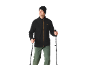 Mann in schwarzem Fleece, grüner Wanderhose und Mütze, der Trekkingstöcke hält.