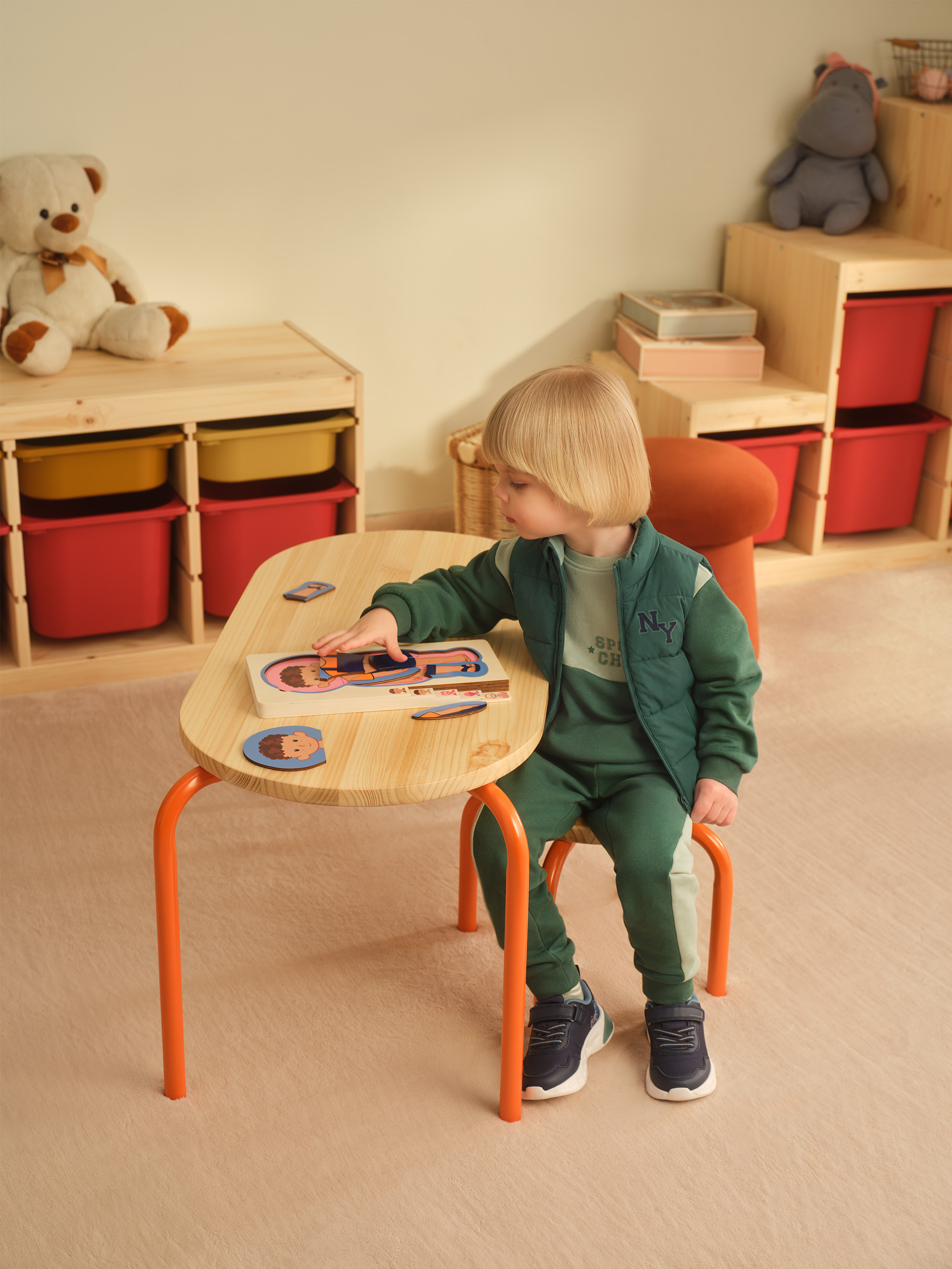 Kind spielt mit einem Holzpuzzle an einem Aktivitätstisch im Kinderzimmer.