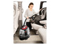 Eine Frau reinigt einen Autositz mit einem Bissell MultiClean Dampfreiniger.