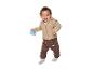 Lächelndes Baby in beiger Jacke und brauner Hose, das eine Rassel hält.