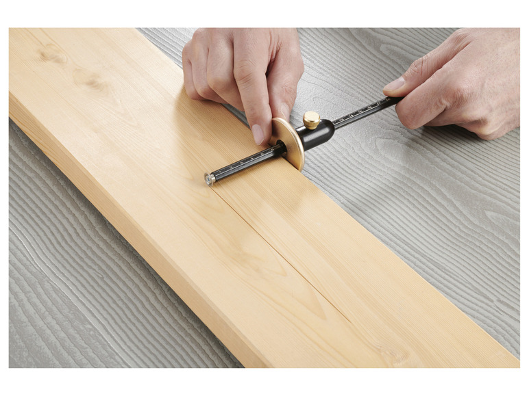 Eine Hand benutzt eine Kreissäge, um eine Linie in ein Holzbrett zu sägen.