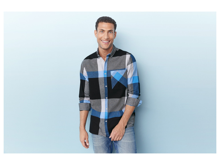 Mann in einem blau-grauen karierten Hemd und blauen Jeans.