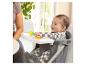 Glückliches Baby sitzt in einem Hochstuhl mit einem Tablett voller bunter Spielzeuge.