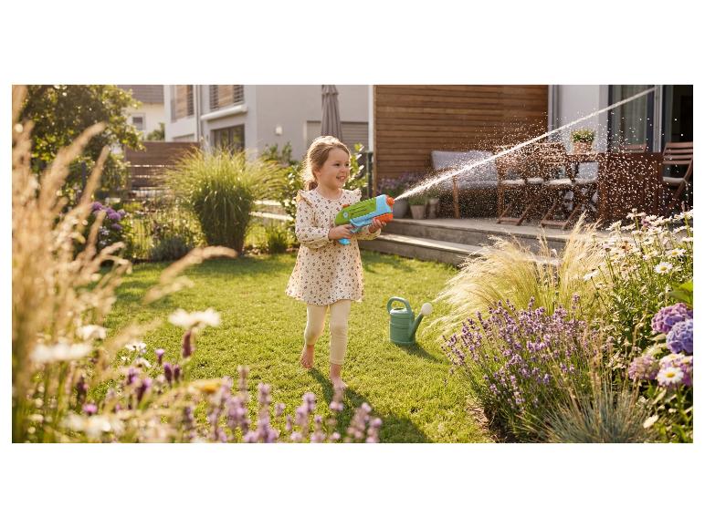 Mädchen spielt mit einer Wasserpistole im Garten.