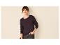 Frau in dunkelblauem Pullover und dunkler Jeans, Hand in der Tasche.