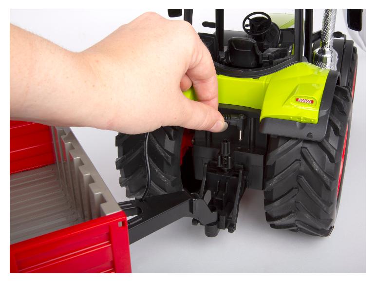 Ein Anhänger wird manuell an einen Bruder-Funktions-Traktor angeschlossen.