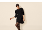 Frau in einem schwarzen Strickkleid und schwarzer Strumpfhose