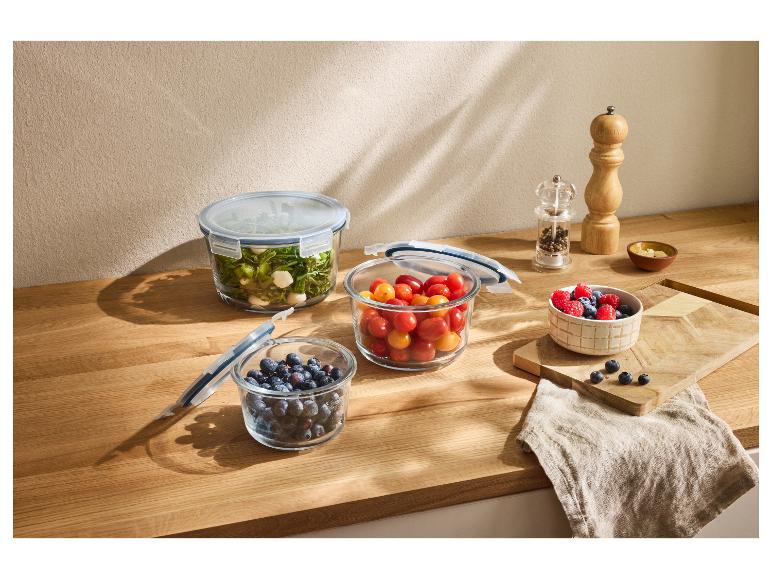 Glasbehälter mit frischen Lebensmitteln auf einer Holztheke.