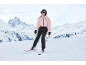 Frau in rosa Skijacke und schwarzer Hose beim Skifahren auf einer verschneiten Piste