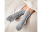 Zwei Paar graue, weiche Socken auf einem Bett.