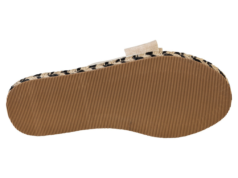 Die Sohle einer beigefarbenen Espadrille mit einem schwarzen Band.