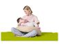 Lächelnde Mutter stillt ihr Baby auf einem Stillkissen, sitzend auf einer grünen Matte.