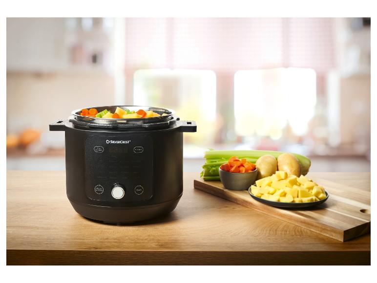 Slow Cooker mit gewürfeltem Gemüse und frischen Zutaten auf einem Holztisch.