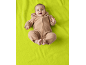 Baby in sandfarbenem Overall liegt auf einer leuchtend grünen Decke.