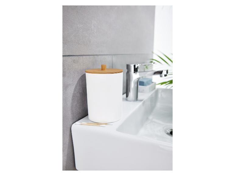 Ein weißer Wattestäbchenbehälter mit Holzdeckel auf einem Waschbecken