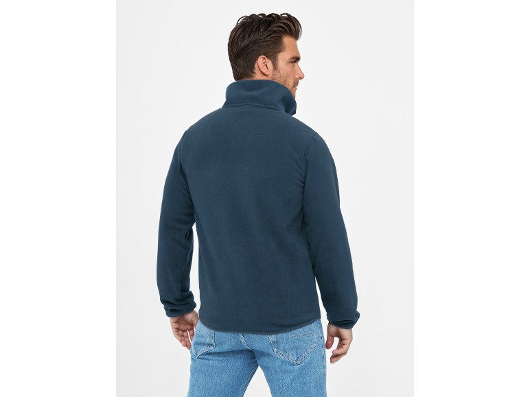 Mann von hinten, trägt eine dunkelblaue Fleecejacke mit Stehkragen und Jeans.