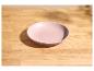 Leere rosa Schale auf einem hellen Holztisch mit Schatten.
