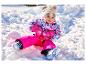 Kleinkind in pinker LUPILU® Schneehose beim Rodeln im Schnee.