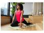 Frau in Yogapose auf einer Matte, trägt ein pinkes Sporttop und schwarze Leggings.