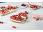 Herzförmiger Käsekuchen mit Beeren, serviert mit Erdbeeren, Himbeeren und Kirschen.