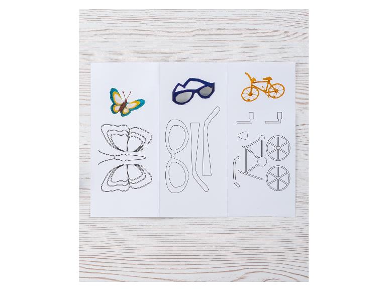 Ein Schmetterling, eine Sonnenbrille und ein Fahrrad, mit ihren Vorlagen, auf einem Holztisch.