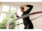Frau in schwarzem Trainingsanzug und Leggings trainiert mit einem Hula-Hoop-Reifen.