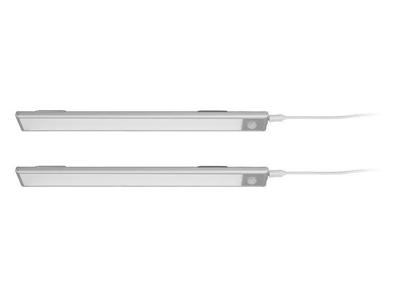 Zwei silberne LED-Unterbauleuchten mit Bewegungssensoren und Ladekabeln.
